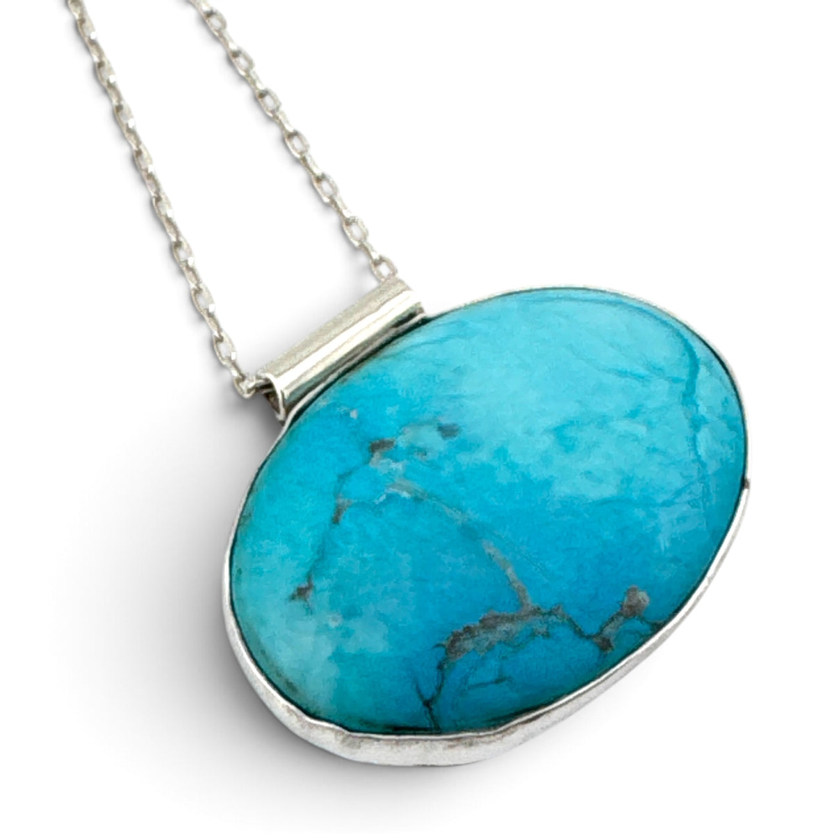 Angled detail showing handmade recycled sterling silver bezel around reclaimed blue stone